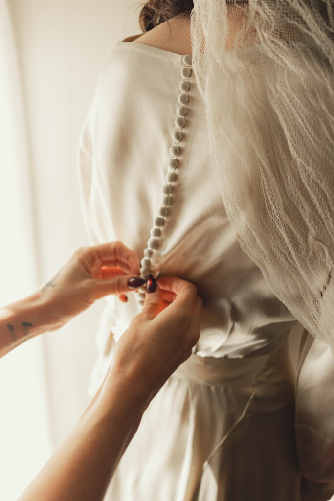 hands buttoning vintage 1930's wedding dress 