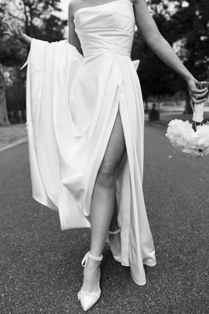 Bride showing off couture wedding dress with slit and bridal high heels in black and white