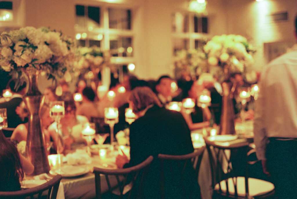 warm lighting wedding reception image of guests enjoying dinner on 35mm film