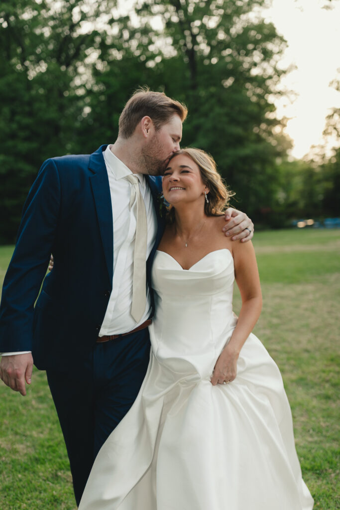 candid photo of groom kissing bride on temple while she smiles in memphis tn