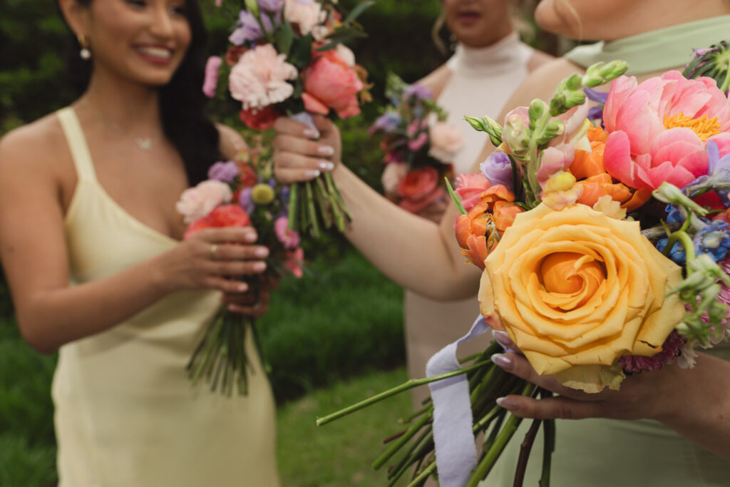 wedding party candid photo of bridesmaids comparing colorful floral bouquets