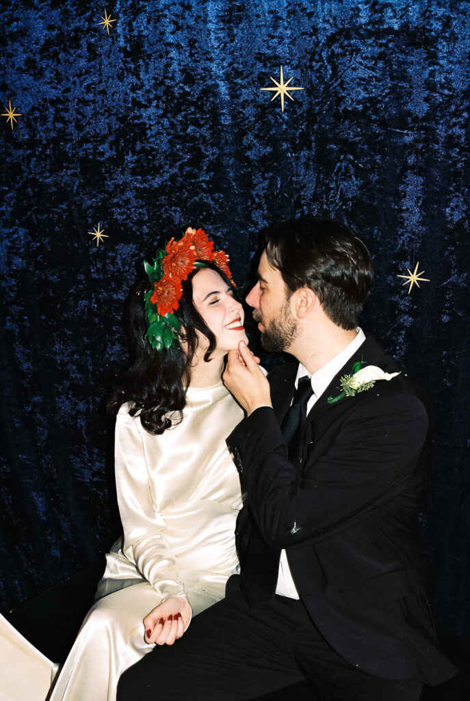 bride and groom sharing kiss on paper moon wedding decor prop photo location with velvet background