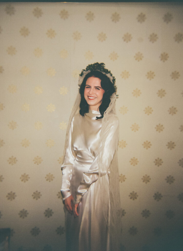 bride posing in front of vintage wallpaper in 1930's wedding gown on 120 film