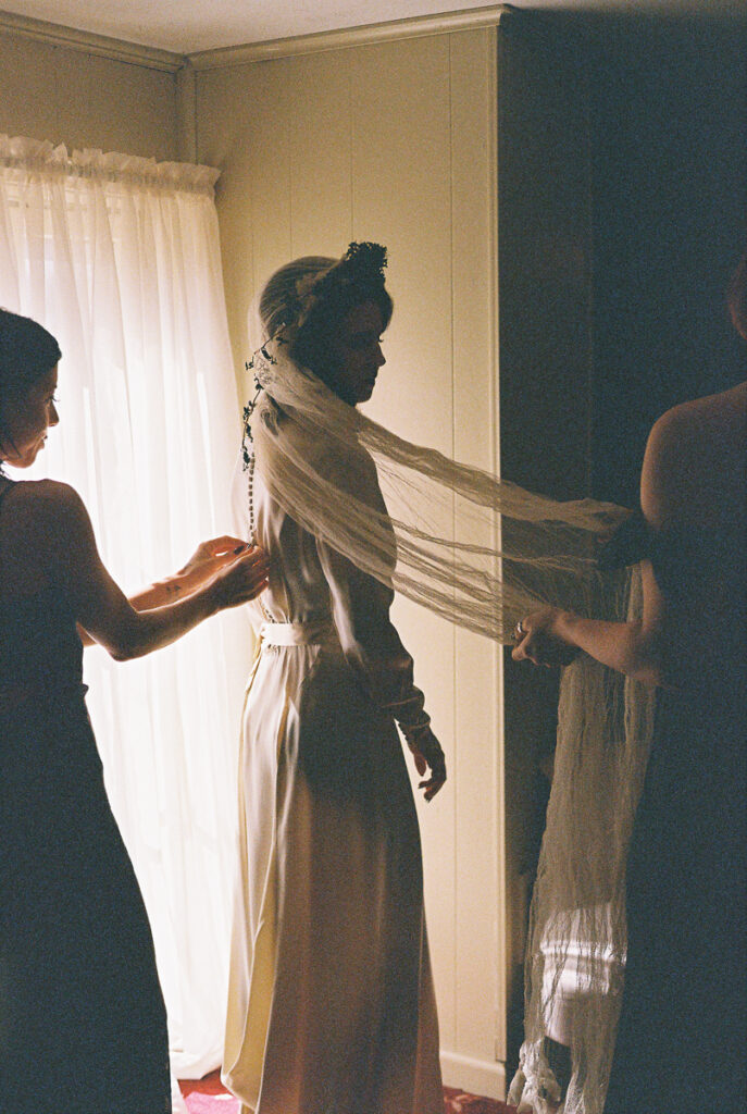 bride getting ready in vintage wedding dress with bridesmaids on film